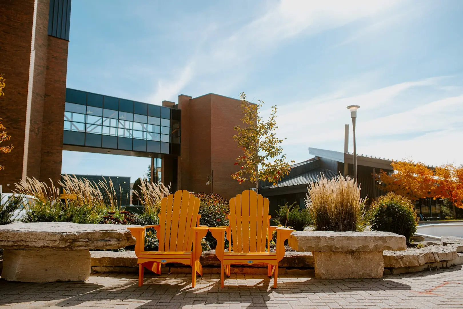 Two yellow chairs on a stone patio in front of a building with a blue sky.