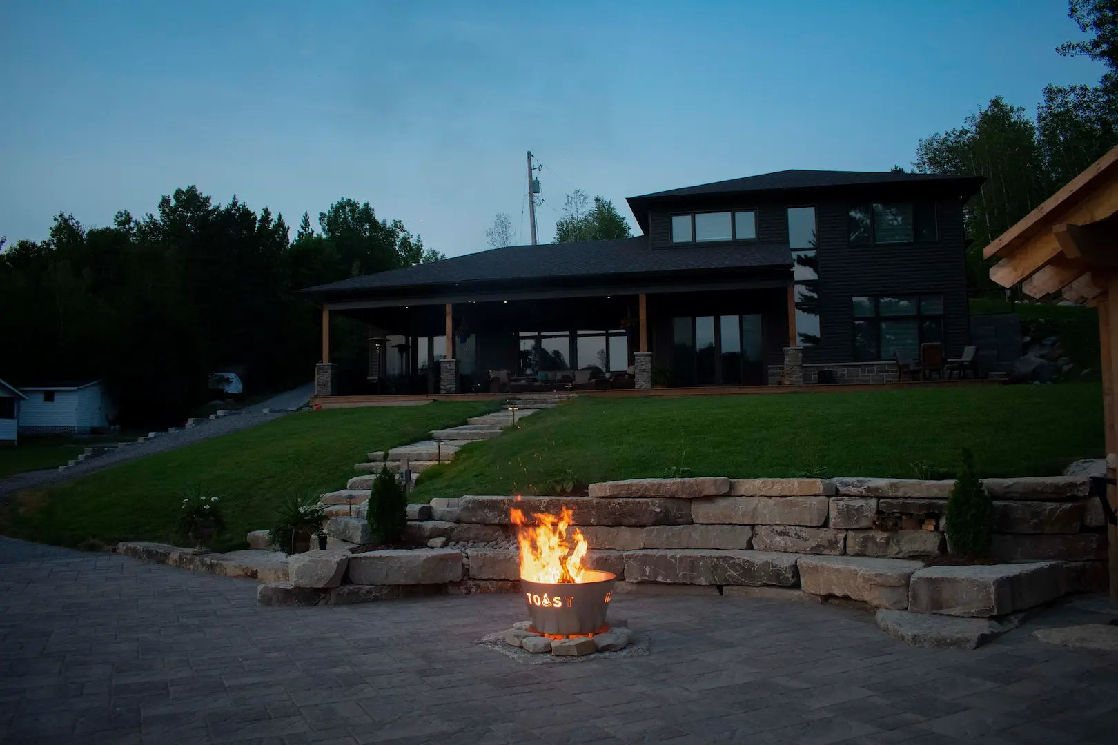 Fire pit in front of a modern house with a evening sky